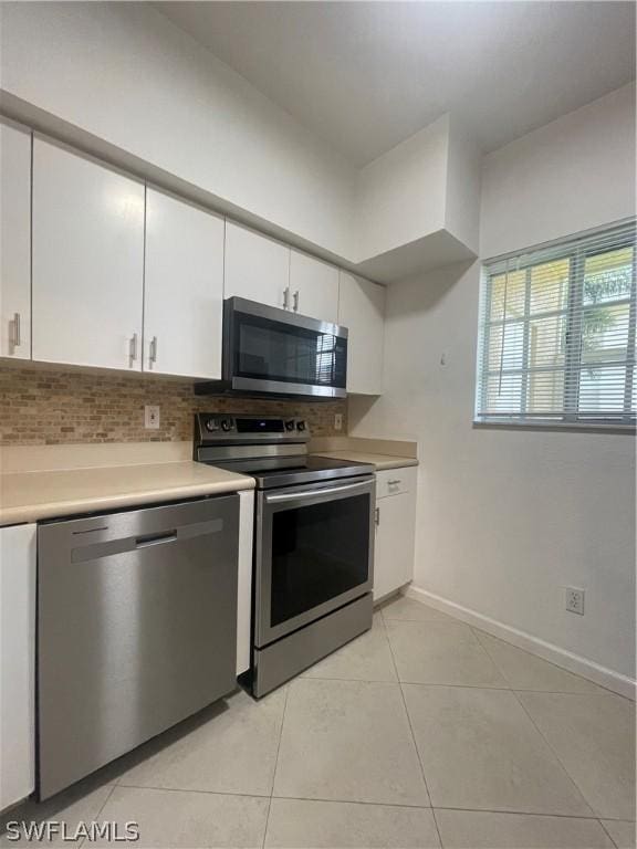 kitchen with decorative backsplash, white cabinets, stainless steel appliances, and light tile patterned floors