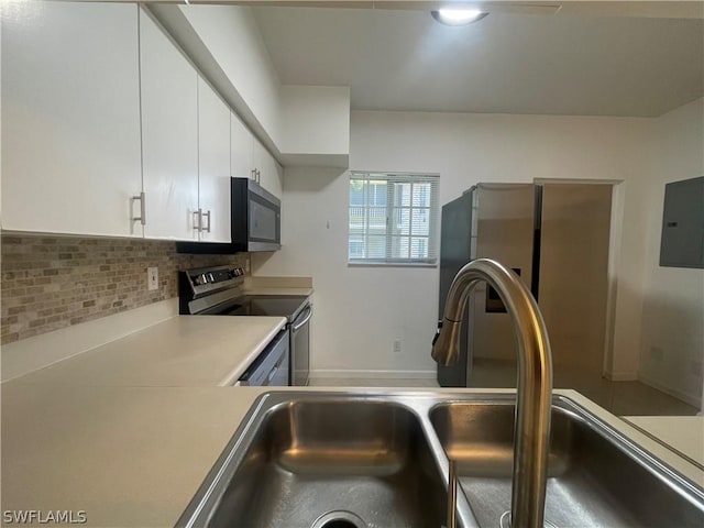 kitchen with appliances with stainless steel finishes, tasteful backsplash, sink, white cabinets, and electric panel