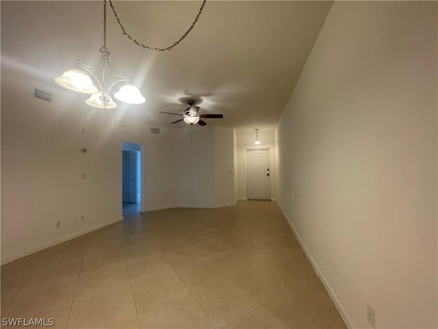 tiled spare room with ceiling fan with notable chandelier