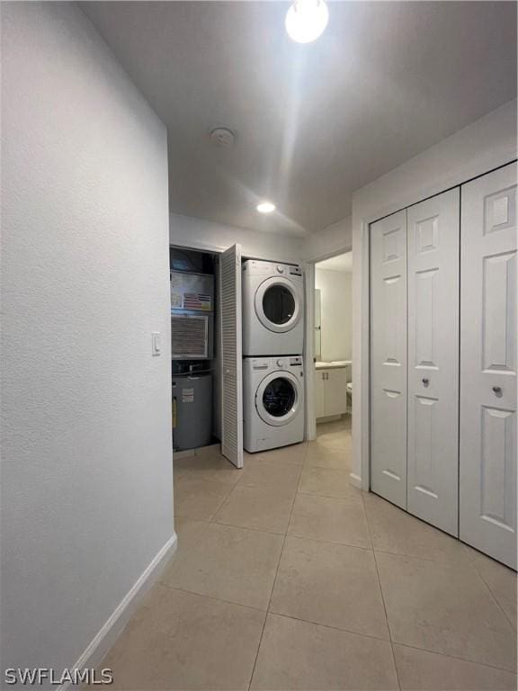 clothes washing area with light tile patterned floors and stacked washer / drying machine