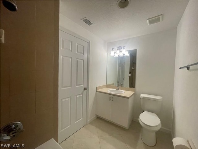 bathroom with tile patterned floors, vanity, a textured ceiling, and toilet