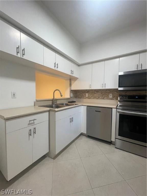 kitchen featuring backsplash, white cabinets, sink, light tile patterned floors, and stainless steel appliances