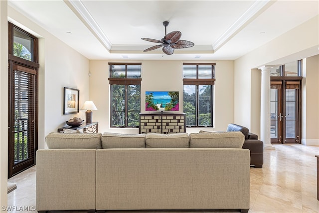 living room featuring ceiling fan, a tray ceiling, crown molding, and decorative columns