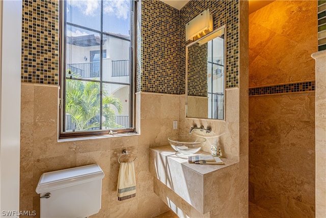 bathroom featuring sink, tile walls, and toilet