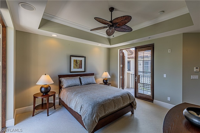 bedroom featuring ceiling fan, access to exterior, and a tray ceiling