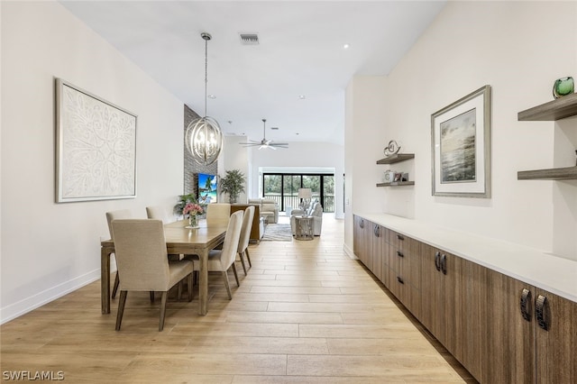 dining room with ceiling fan with notable chandelier and light wood-type flooring