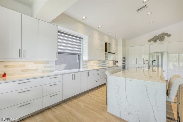 kitchen with stainless steel appliances, white cabinetry, and a kitchen island with sink