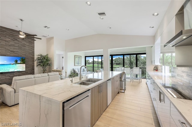 kitchen with light stone countertops, dishwasher, an island with sink, wall chimney range hood, and sink