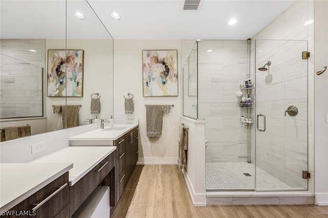 bathroom featuring hardwood / wood-style flooring, walk in shower, and vanity