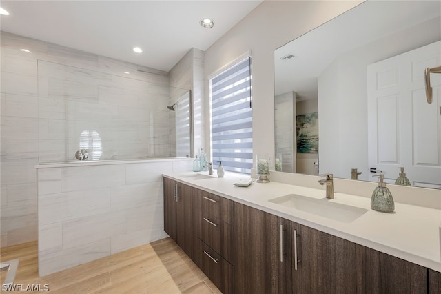 bathroom with tiled shower and vanity