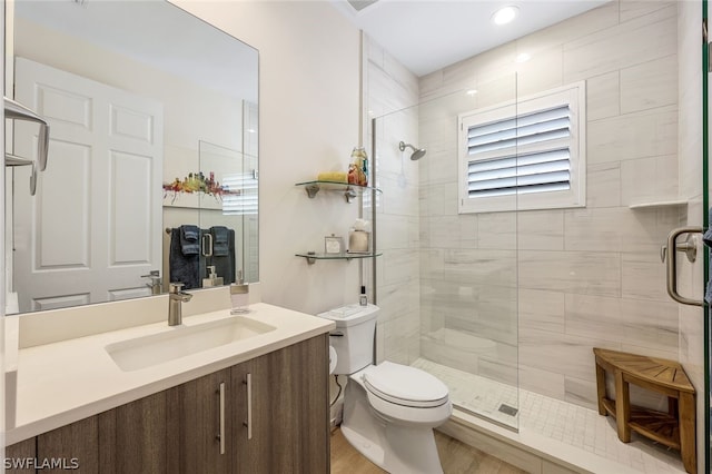 bathroom with toilet, wood-type flooring, vanity, and a shower with shower door