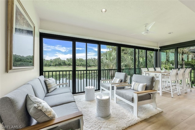 sunroom / solarium with ceiling fan and a water view