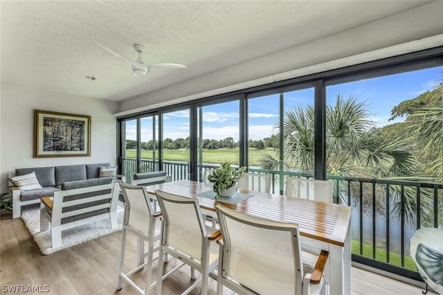 sunroom featuring ceiling fan and a water view