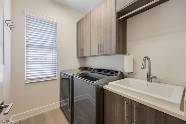 laundry room with sink, light wood-type flooring, separate washer and dryer, and cabinets