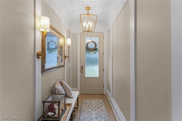 doorway with a chandelier, light hardwood / wood-style floors, and ornamental molding