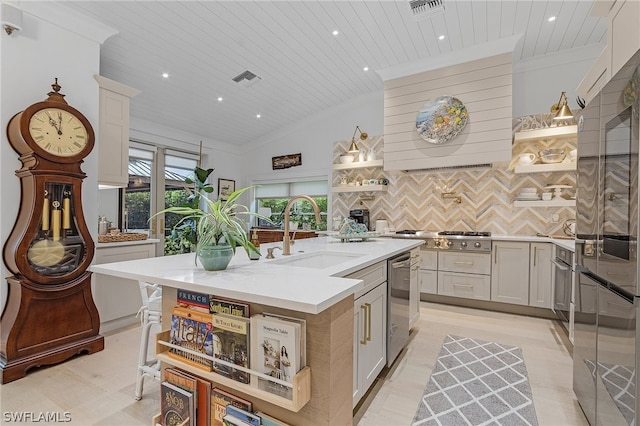 kitchen with wooden ceiling, a center island with sink, sink, vaulted ceiling, and decorative backsplash