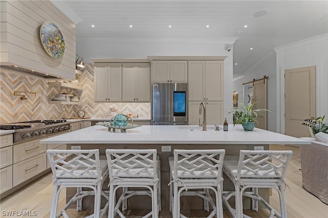 kitchen with a kitchen bar, a barn door, stainless steel appliances, and tasteful backsplash