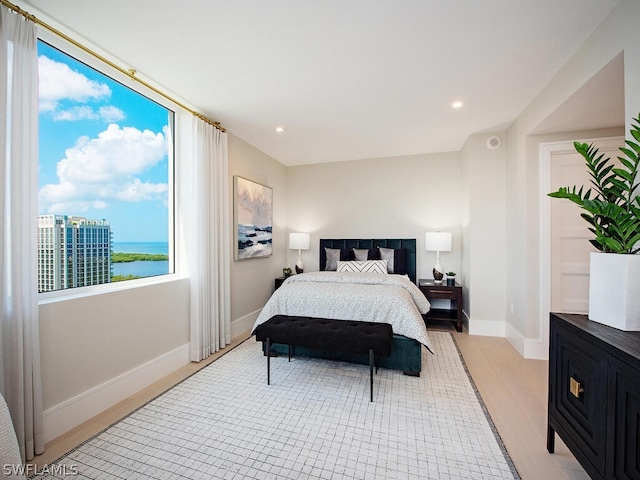 bedroom featuring a water view and light wood-type flooring