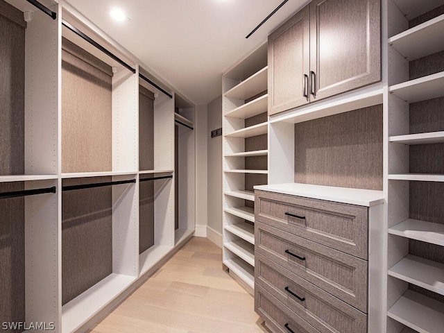 walk in closet with light hardwood / wood-style floors