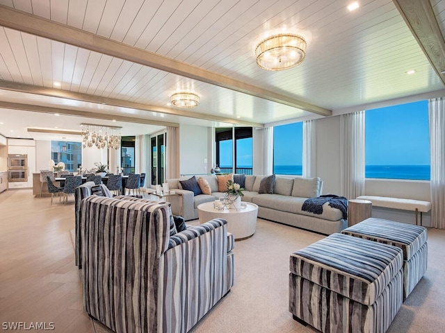 living room featuring a water view, beam ceiling, hardwood / wood-style flooring, and a chandelier