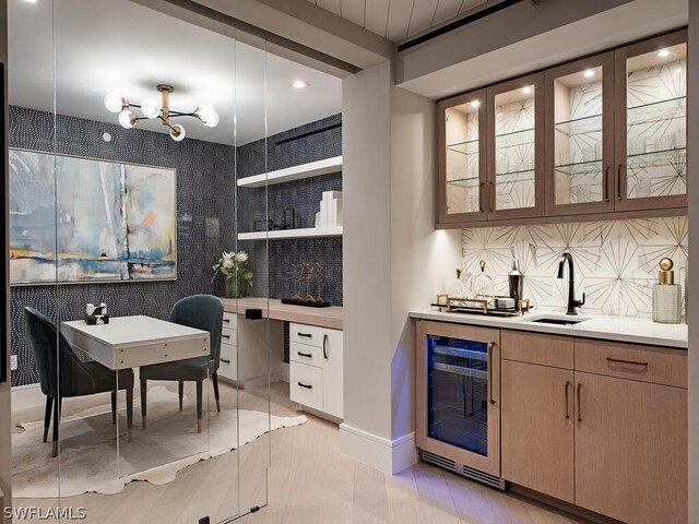 bar with a chandelier, sink, tasteful backsplash, and beverage cooler