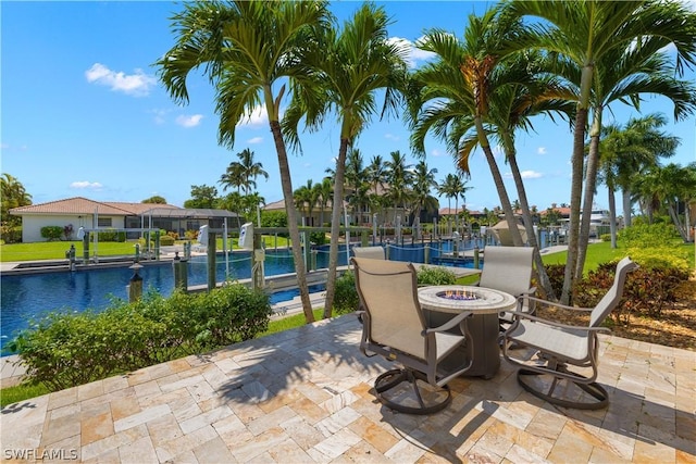 view of patio with a fire pit, a water view, and a community pool