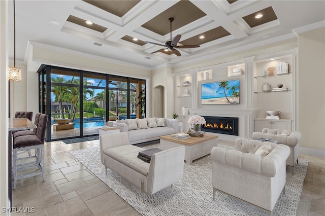 living area featuring a warm lit fireplace, ornamental molding, coffered ceiling, and a towering ceiling