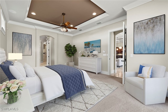 bedroom featuring arched walkways, a tray ceiling, light carpet, and visible vents