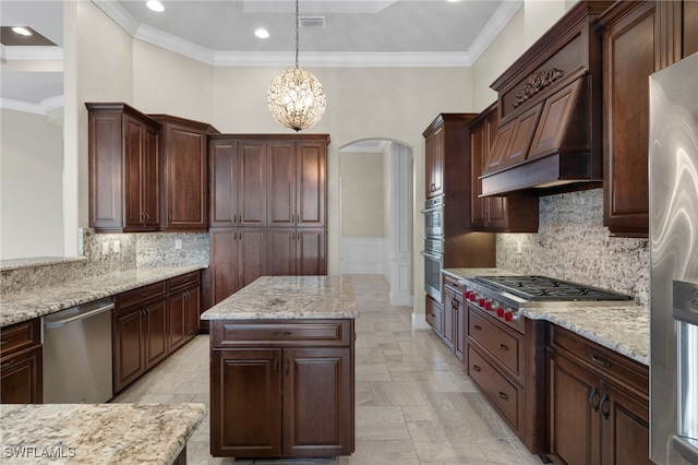 kitchen featuring arched walkways, custom exhaust hood, stainless steel appliances, hanging light fixtures, and ornamental molding