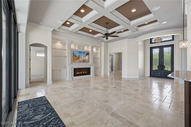 unfurnished living room with plenty of natural light, a high ceiling, coffered ceiling, and a lit fireplace