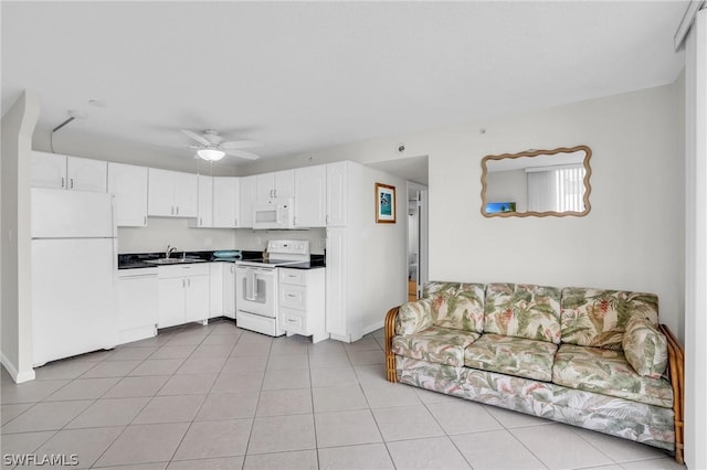 kitchen featuring white appliances, light tile patterned floors, a sink, white cabinetry, and dark countertops