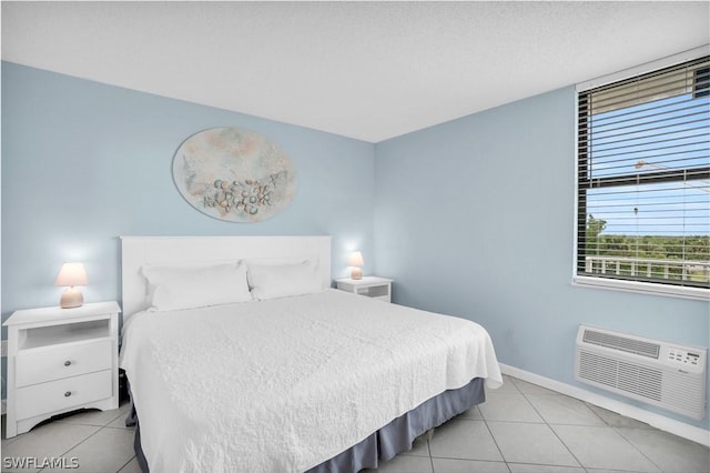 bedroom featuring an AC wall unit, light tile patterned floors, and baseboards