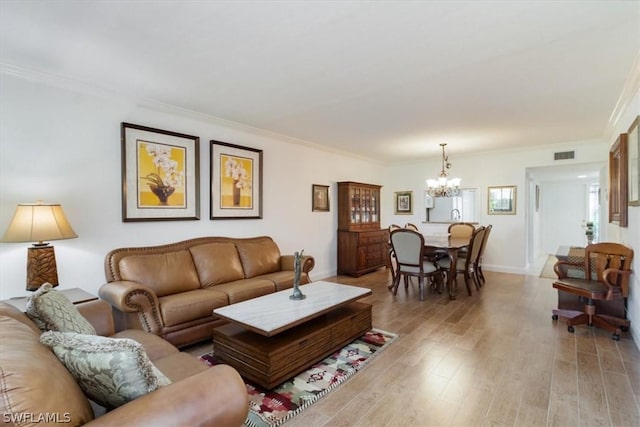 living room with crown molding, light wood-type flooring, and a notable chandelier