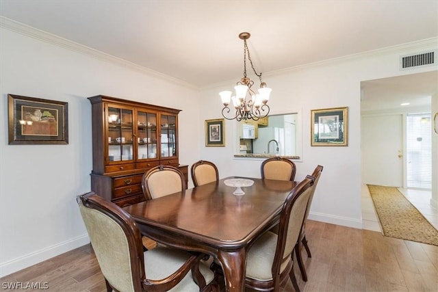 dining area with a chandelier, wood-type flooring, and ornamental molding