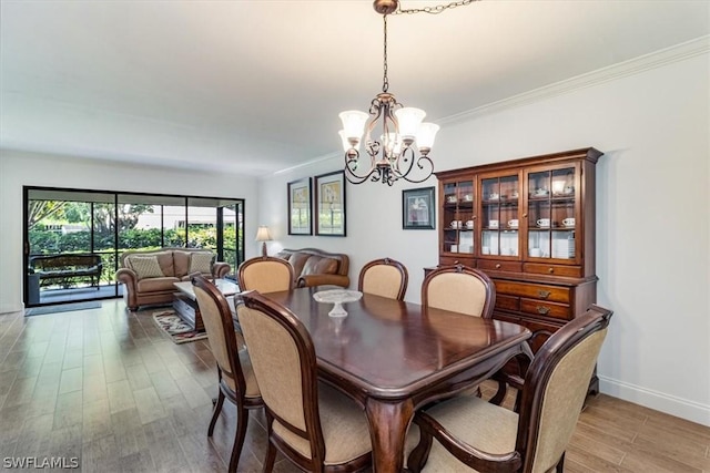 dining space featuring a notable chandelier, light wood-type flooring, and crown molding