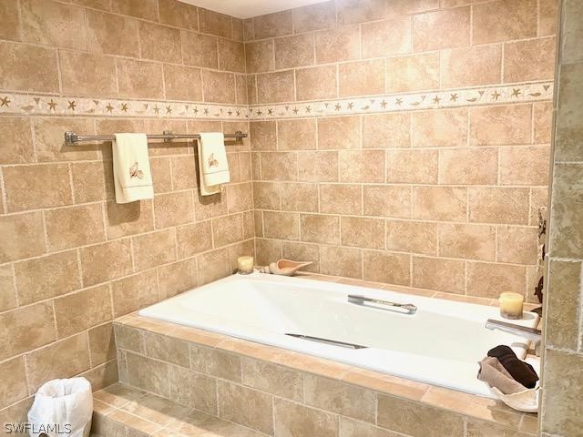 bathroom with tile walls and tiled bath