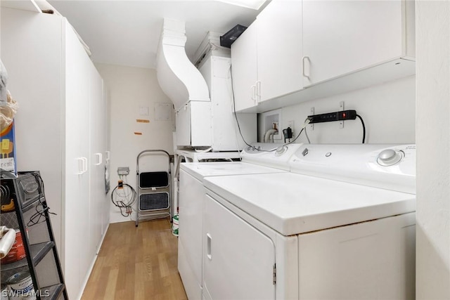 clothes washing area featuring cabinet space, washer and clothes dryer, and light wood finished floors