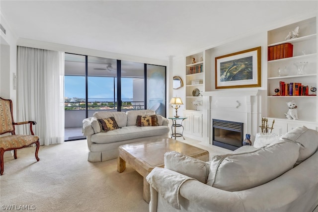 carpeted living area with a fireplace with flush hearth, built in shelves, floor to ceiling windows, and a ceiling fan