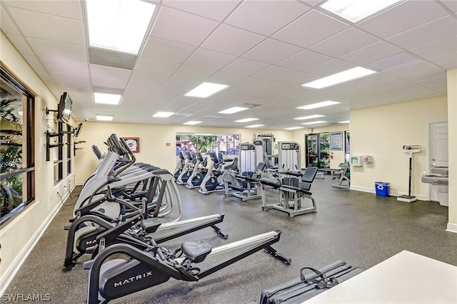 workout area featuring a drop ceiling and baseboards