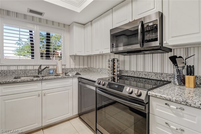 kitchen featuring sink, stainless steel appliances, white cabinets, and light tile patterned floors