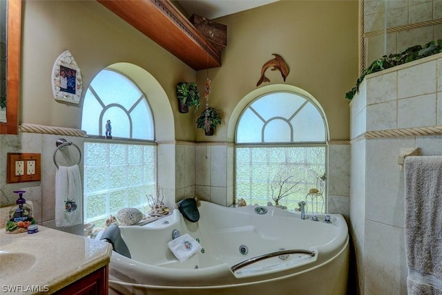 bathroom featuring vanity, a bathtub, tile walls, and a wealth of natural light