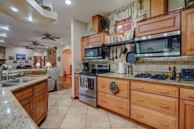 kitchen featuring light tile patterned flooring, sink, stainless steel appliances, light stone countertops, and decorative backsplash