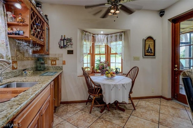 tiled dining area with plenty of natural light, wet bar, and ceiling fan