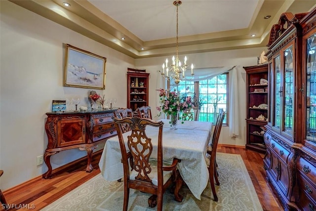 dining room featuring an inviting chandelier, dark hardwood / wood-style floors, and a raised ceiling