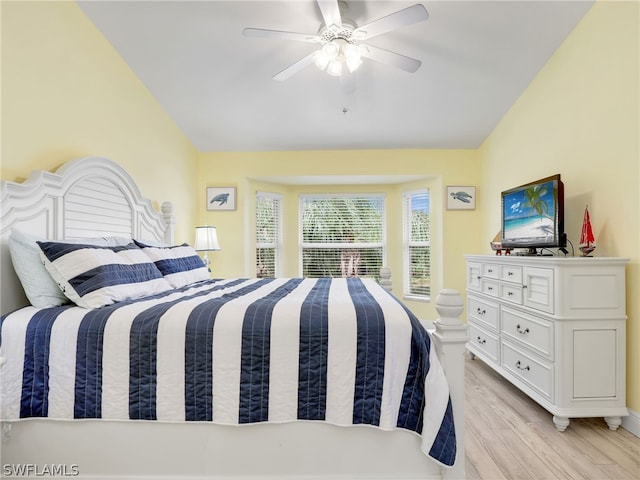 bedroom with ceiling fan, light hardwood / wood-style floors, and vaulted ceiling