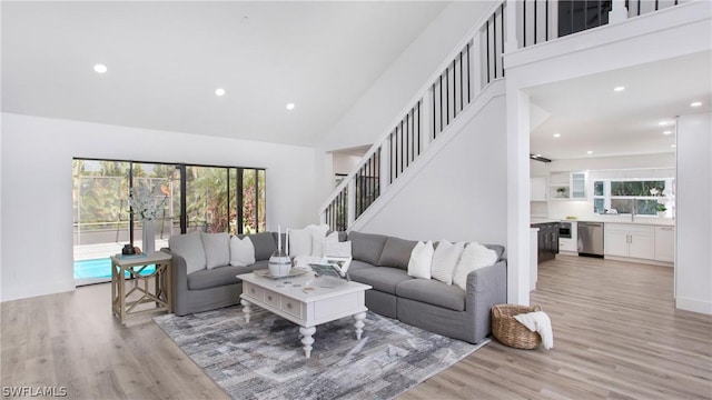 living room featuring plenty of natural light, high vaulted ceiling, and light wood-type flooring