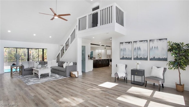 living room featuring hardwood / wood-style flooring, ceiling fan, and high vaulted ceiling