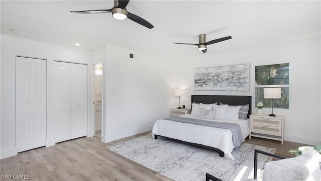 bedroom featuring multiple closets, ceiling fan, and light hardwood / wood-style floors