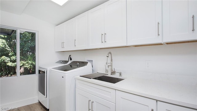 laundry room with cabinets, separate washer and dryer, sink, and light wood-type flooring