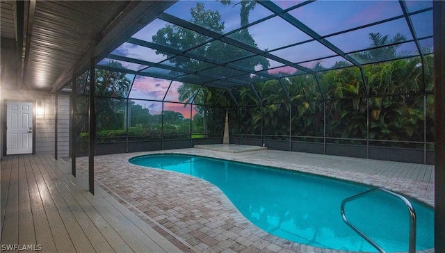 pool at dusk with a lanai and a patio area